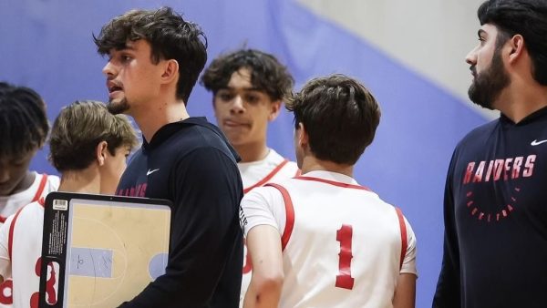 Coach Gonzalez meticulously instructs the players what to do on their next play while the teammates behind him discuss how to react to the game's lessons. 