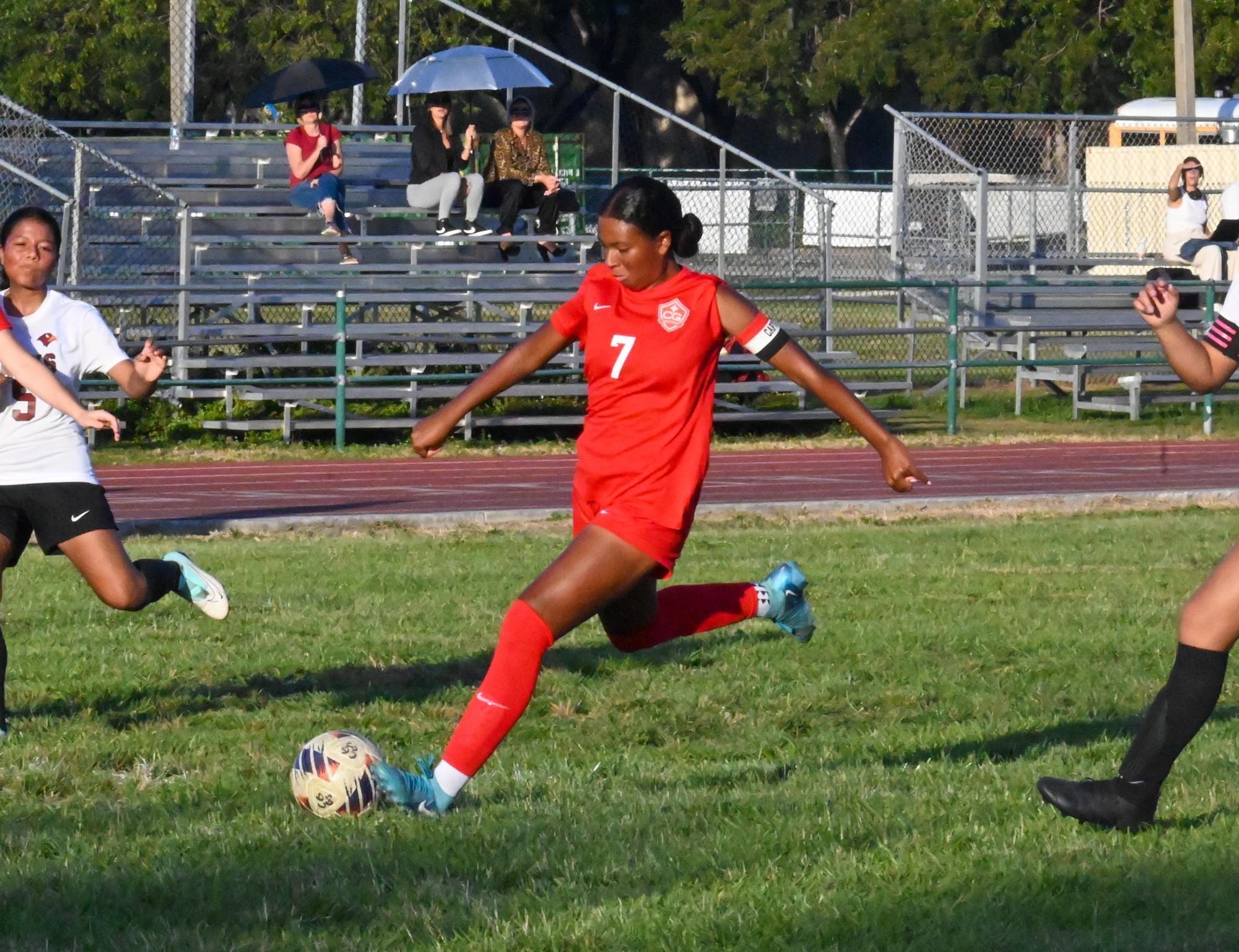 On the field, Lawson powerfully kicks the ball toward the goal. Her focus and determination are easily seen as she drives the play forward.